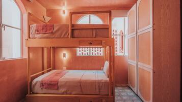 A bunk bed room with a window, a wardrobe, and a patterned floor.