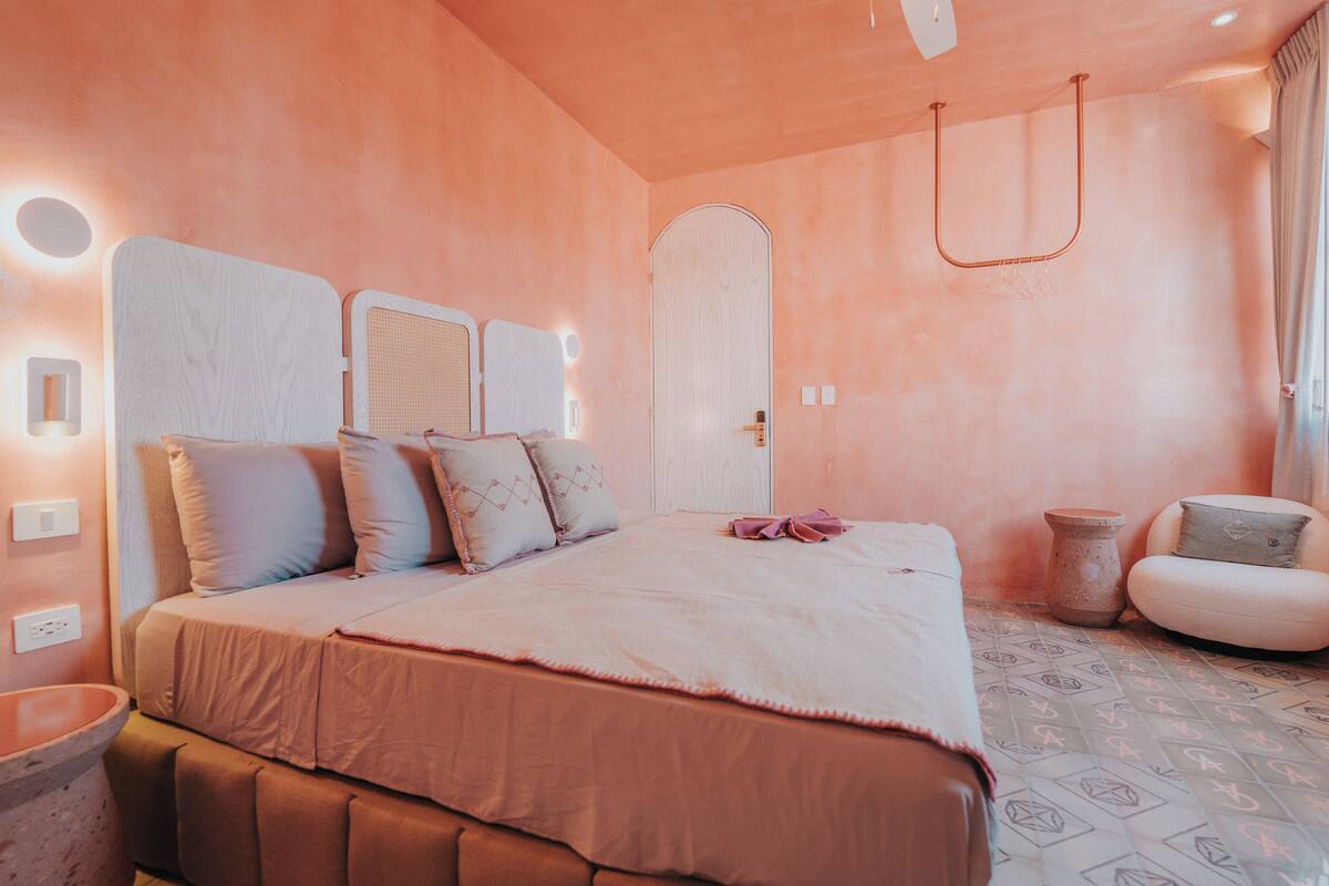 A bedroom with a large bed, a bedside table, a chair, and a small table.