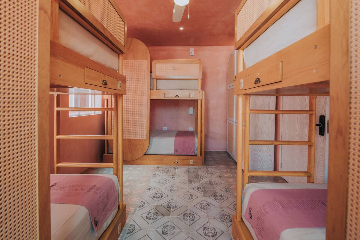A compact room with bunk beds, a ceiling fan, and patterned floor tiles.