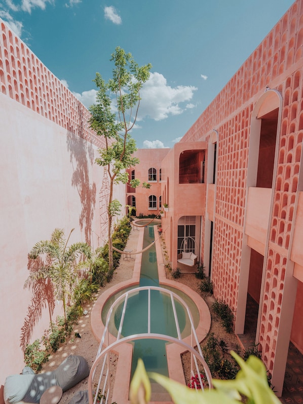 A courtyard with a pool, surrounded by pink buildings with arched windows and a clear sky. - Casa Amate 61 - Mérida Centro (Mérida)