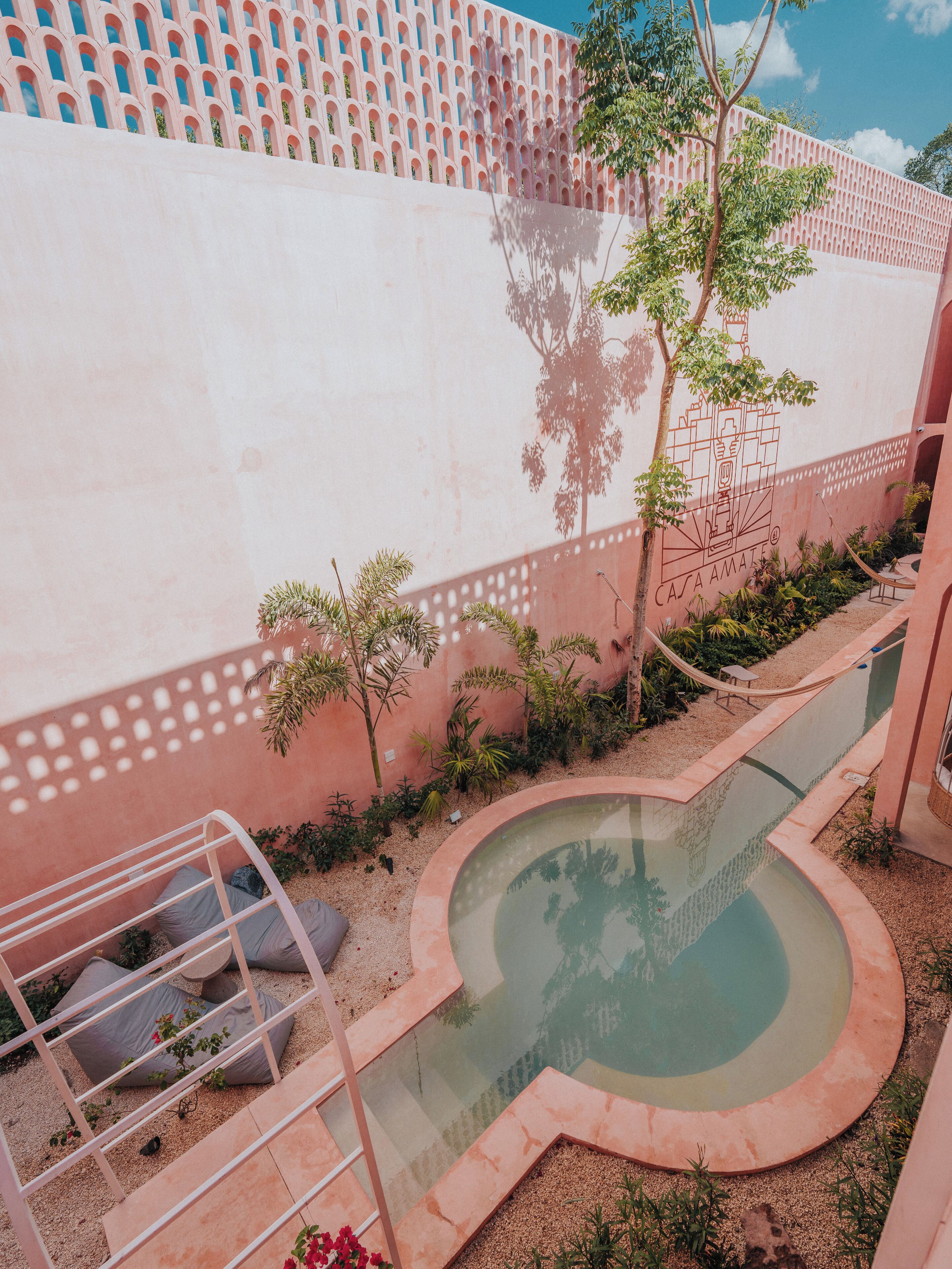 Uma área de piscina com uma piscina circular, uma rede e uma escadaria que leva a uma varanda.