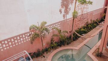Uma área de piscina com uma piscina circular, uma rede e uma escadaria que leva a uma varanda.