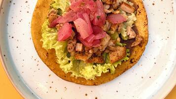 A taco with lettuce and pink pickled onions on a plate.