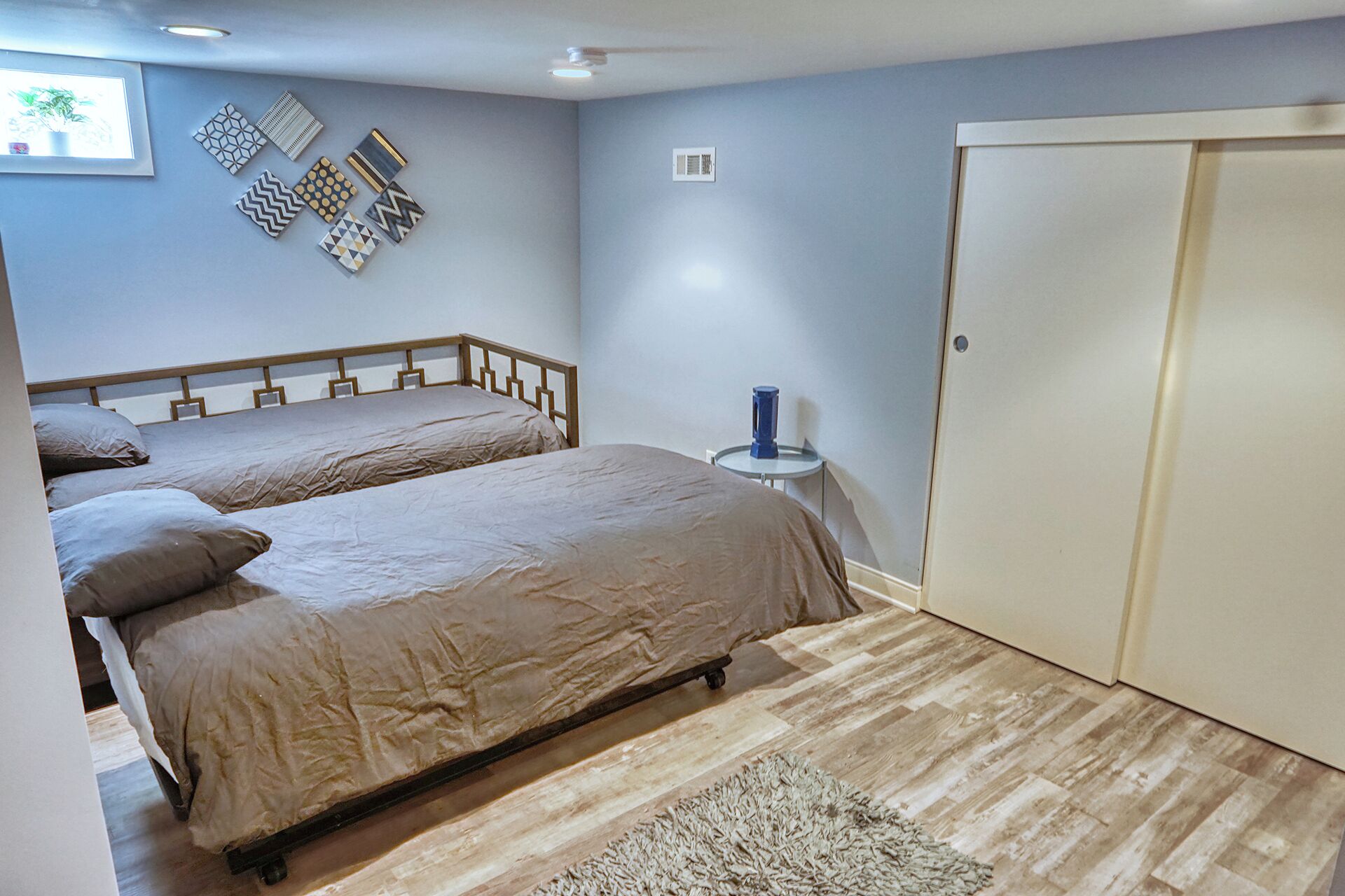A bedroom with two beds, a small round table, and a wardrobe.