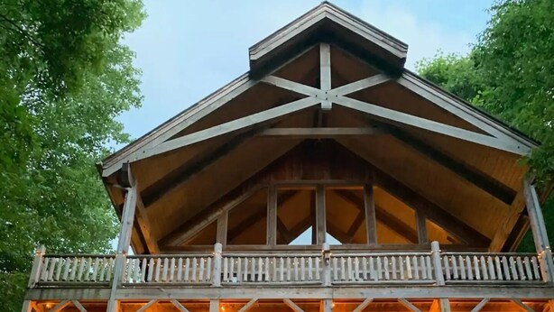 A wooden cabin with a balcony and string lights.