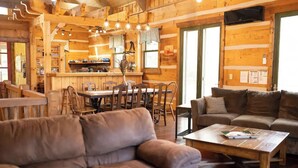 A cozy cabin interior with a dining area, a sofa, and a coffee table.