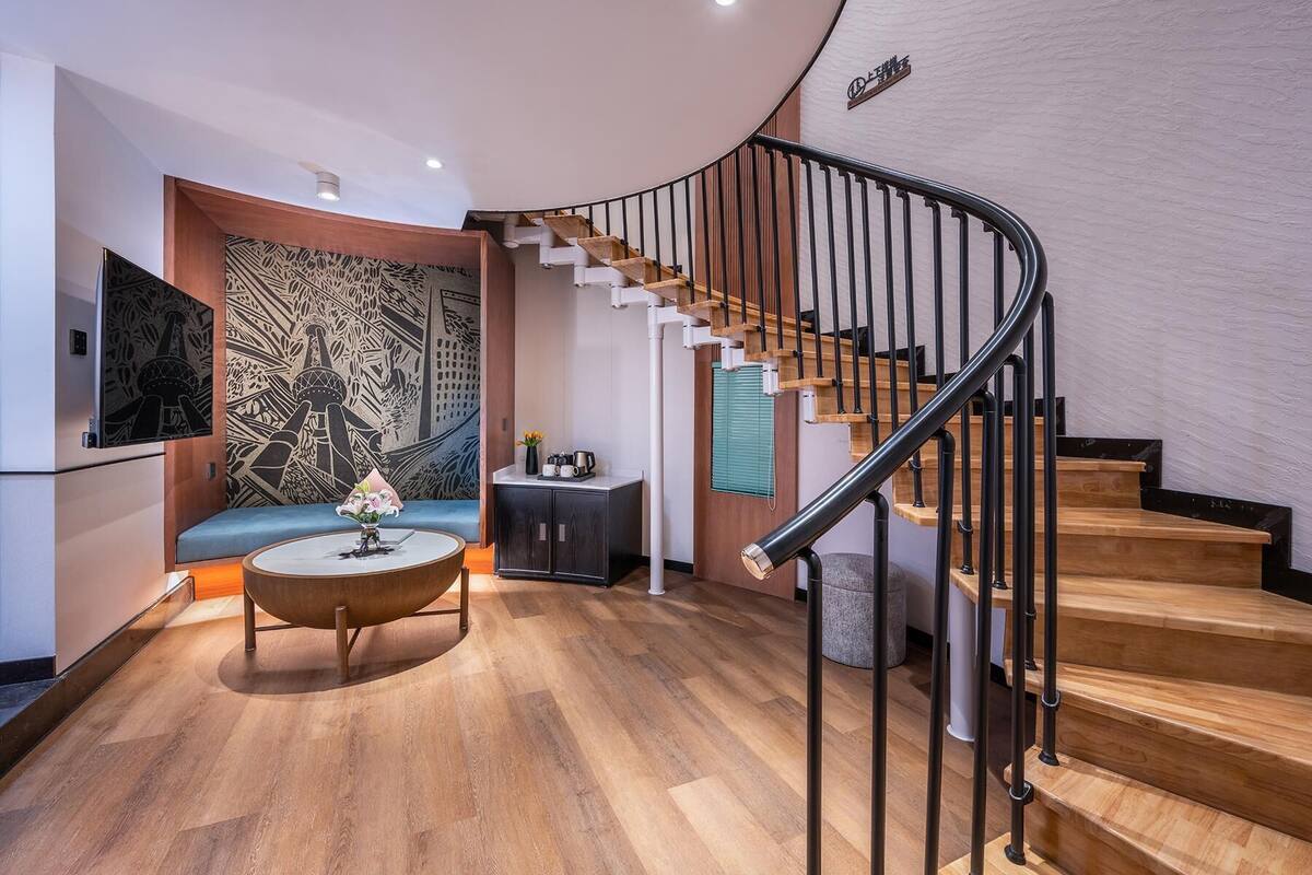 A modern interior with a curved staircase, a seating area with a round table, and a decorative wall.