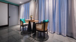 A hotel room with a large window, two chairs, a small round table, and a vase with flowers. - Manxin Hotel Shanghai Songjiang Yunjian (Shanghai)