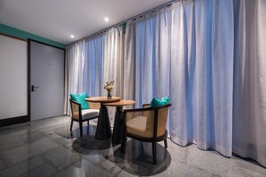 A hotel room with a large window, two chairs, a small round table, and a vase with flowers. - Manxin Hotel Shanghai Songjiang Yunjian (Shanghai)