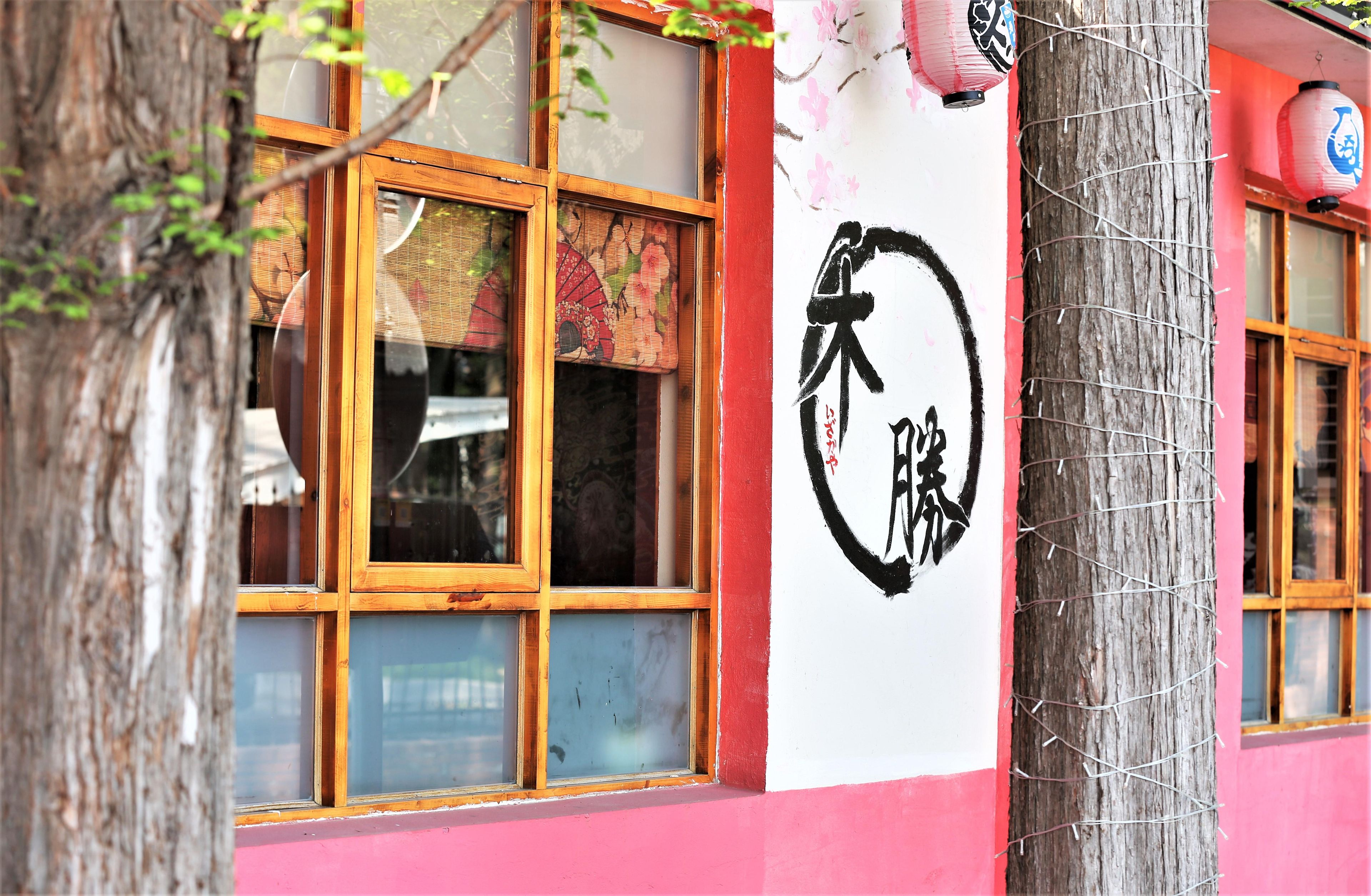A building with traditional Japanese windows and a large sign with Japanese characters.