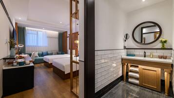 A hotel room with a bed, a desk, a sofa, a bathroom with a sink and mirror.