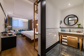 Habitació d'hotel amb llit, escriptori, sofà i bany amb rentapans i mirall.