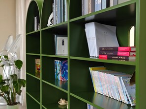 A bookshelf with various books, a white plate, and a small plant. - Manxin Hotel Shanghai Songjiang Yunjian (Shanghai)