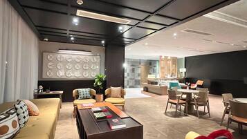 A modern hotel lobby with a seating area, a reception desk, and a wall with clocks.