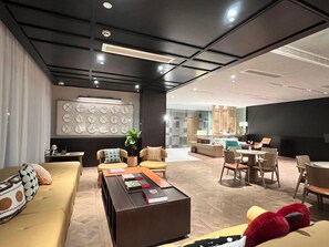 Un moderno vestíbulo de hotel con una zona de estar, una recepción y una pared con relojes.