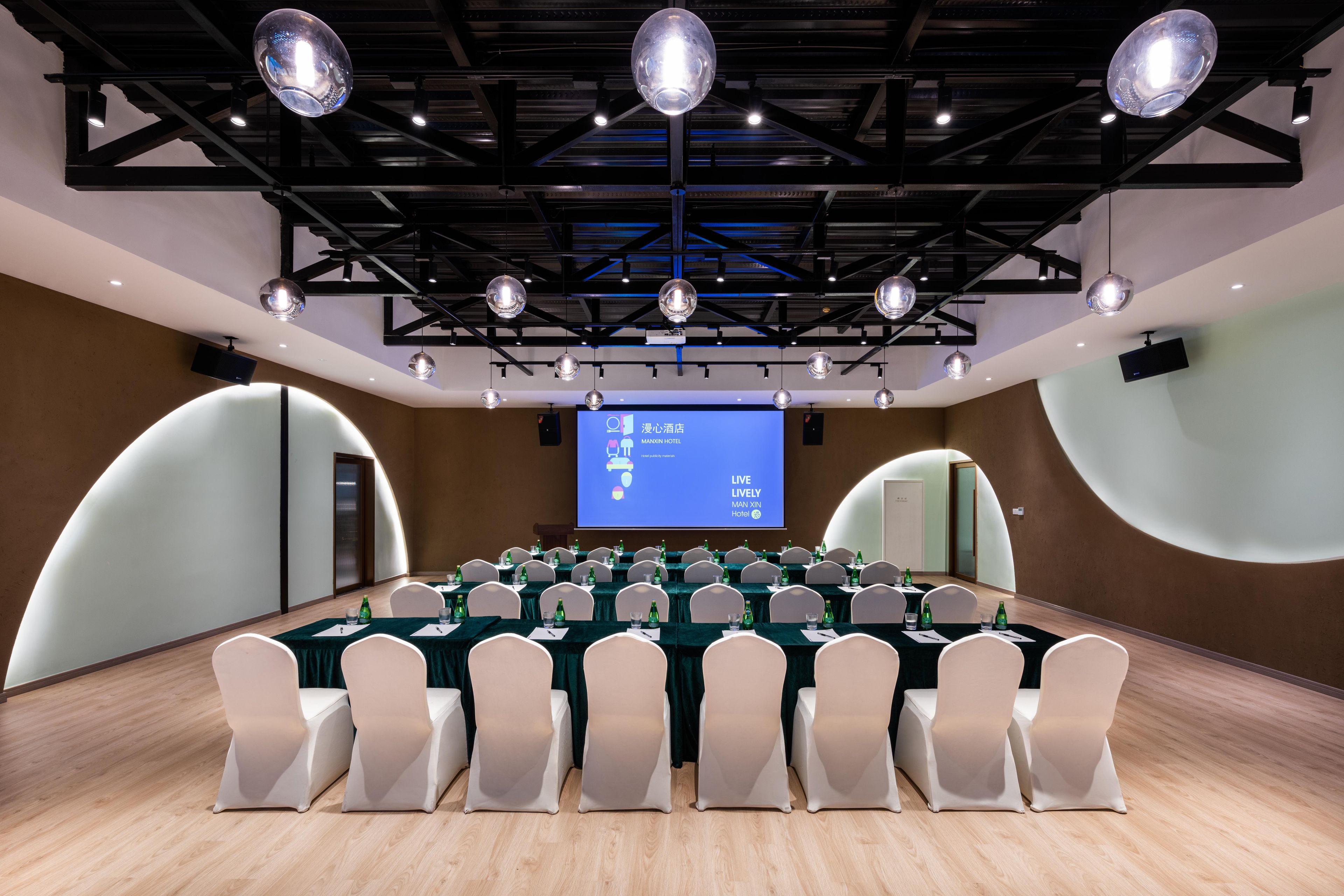 A conference room with a large screen, white chairs, and tables set up for a meeting.
