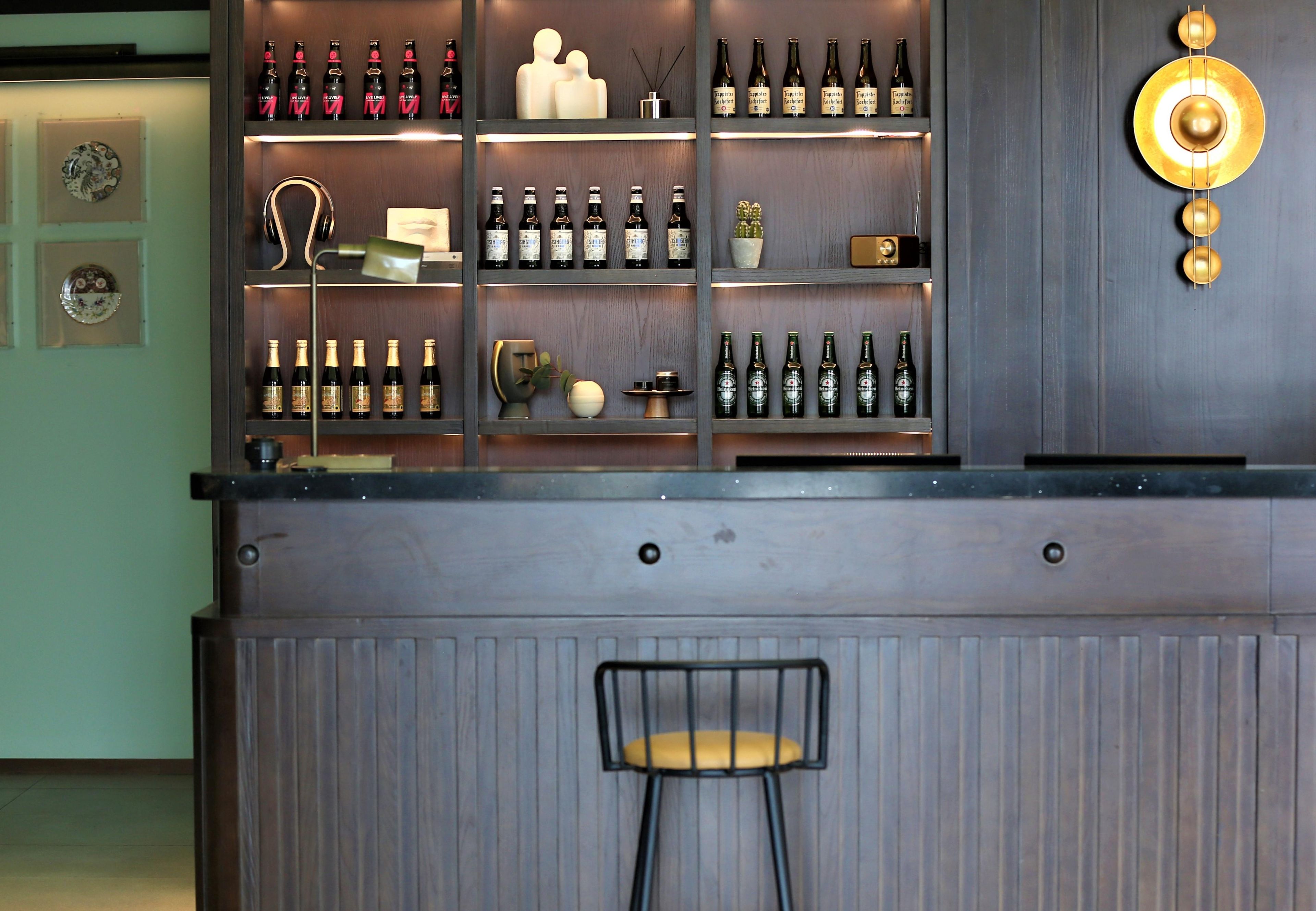 A bar area with shelves of bottles, a stool, and decorative items.