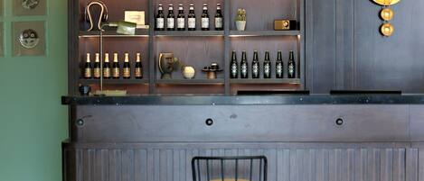 A bar area with shelves of bottles, a stool, and decorative items.