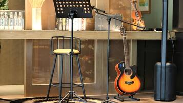 A music studio with a stool, a music stand, a guitar, and a microphone stand.