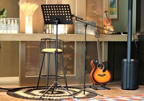 Un estudio de música con un taburete, un atril, una guitarra y un soporte para micrófono.