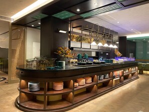 Un moderno bar con una isla central, estantes con platos apilados y lámparas colgantes.