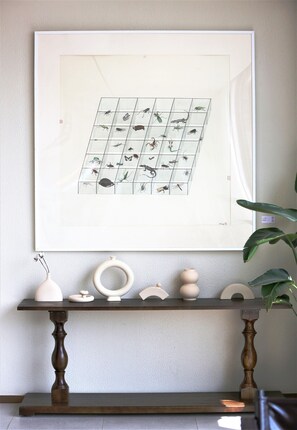 A framed artwork of insects on a wall, a wooden console table with decorative items, and a potted plant. - Manxin Hotel Shanghai Songjiang Yunjian (Shanghai)