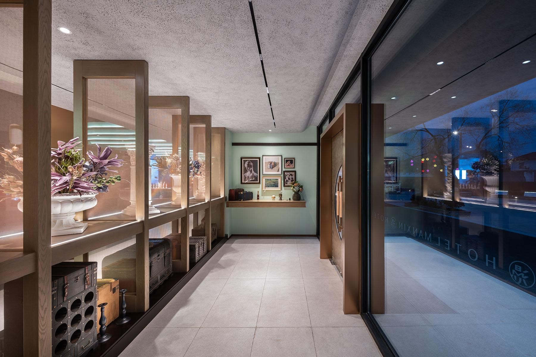 A hallway with a wooden floor, a reception desk, and a wall with framed pictures.