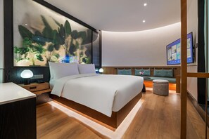 A modern bedroom with a large bed, a bedside table with a lamp, a seating area with a bench, and a wall-mounted TV. - Manxin Hotel Shanghai Songjiang Yunjian (Shanghai)
