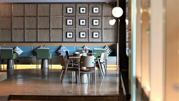 A modern restaurant with a blue and grey color scheme, featuring a seating area with tables and chairs, and a wall decorated with framed pictures.