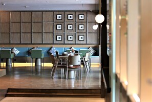 A modern restaurant with a blue and grey color scheme, featuring a seating area with tables and chairs, and a wall decorated with framed pictures. - Manxin Hotel Shanghai Songjiang Yunjian (Shanghai)