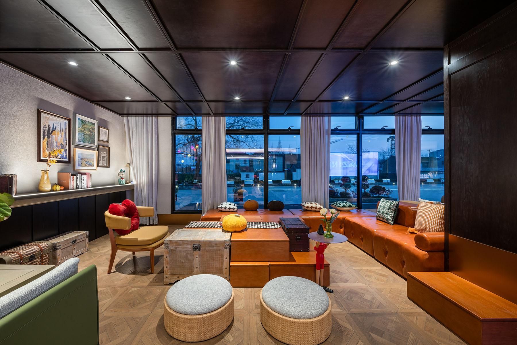 A modern living room with a sofa, ottomans, a coffee table, and a bookshelf.