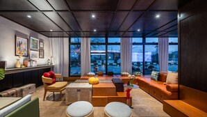 A modern living room with a sofa, ottomans, a coffee table, and a bookshelf. - Manxin Hotel Shanghai Songjiang Yunjian (Shanghai)
