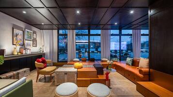 A modern living room with a sofa, ottomans, a coffee table, and a bookshelf.
