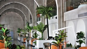 A modern hotel lobby with curved ceiling arches, a reception desk, seating areas, and various indoor plants. - Manxin Hotel Shanghai Songjiang Yunjian (Shanghai)