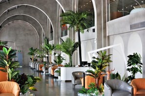 A modern hotel lobby with curved ceiling arches, a reception desk, seating areas, and various indoor plants. - Manxin Hotel Shanghai Songjiang Yunjian (Shanghai)