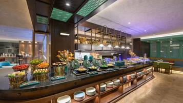 A buffet area with various food items and a seating area with tables and chairs.