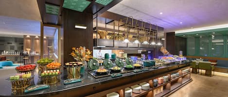A buffet area with various food items and a seating area with tables and chairs.