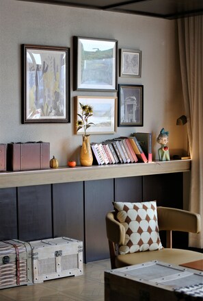 A room with a bookshelf, framed pictures, a vase with flowers, and a decorative figurine. - Manxin Hotel Shanghai Songjiang Yunjian (Shanghai)