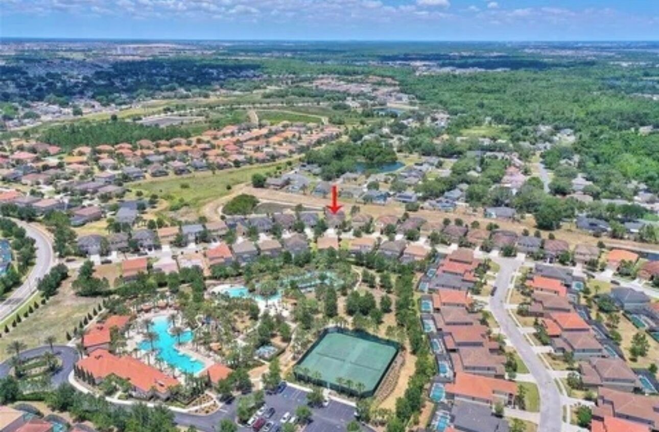 An aerial view of a residential area with houses, a swimming pool, and a tennis court.