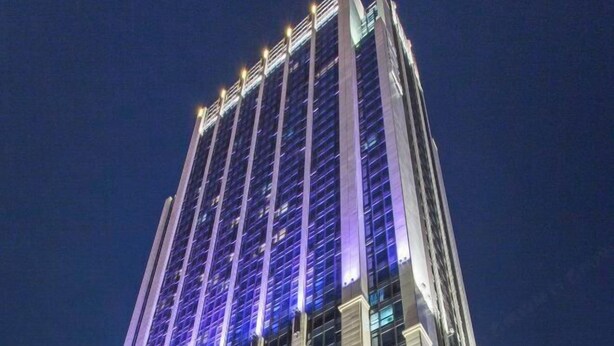 Un edificio di grandi dimensioni con un design architettonico moderno, caratterizzato da linee verticali e finestre illuminate.