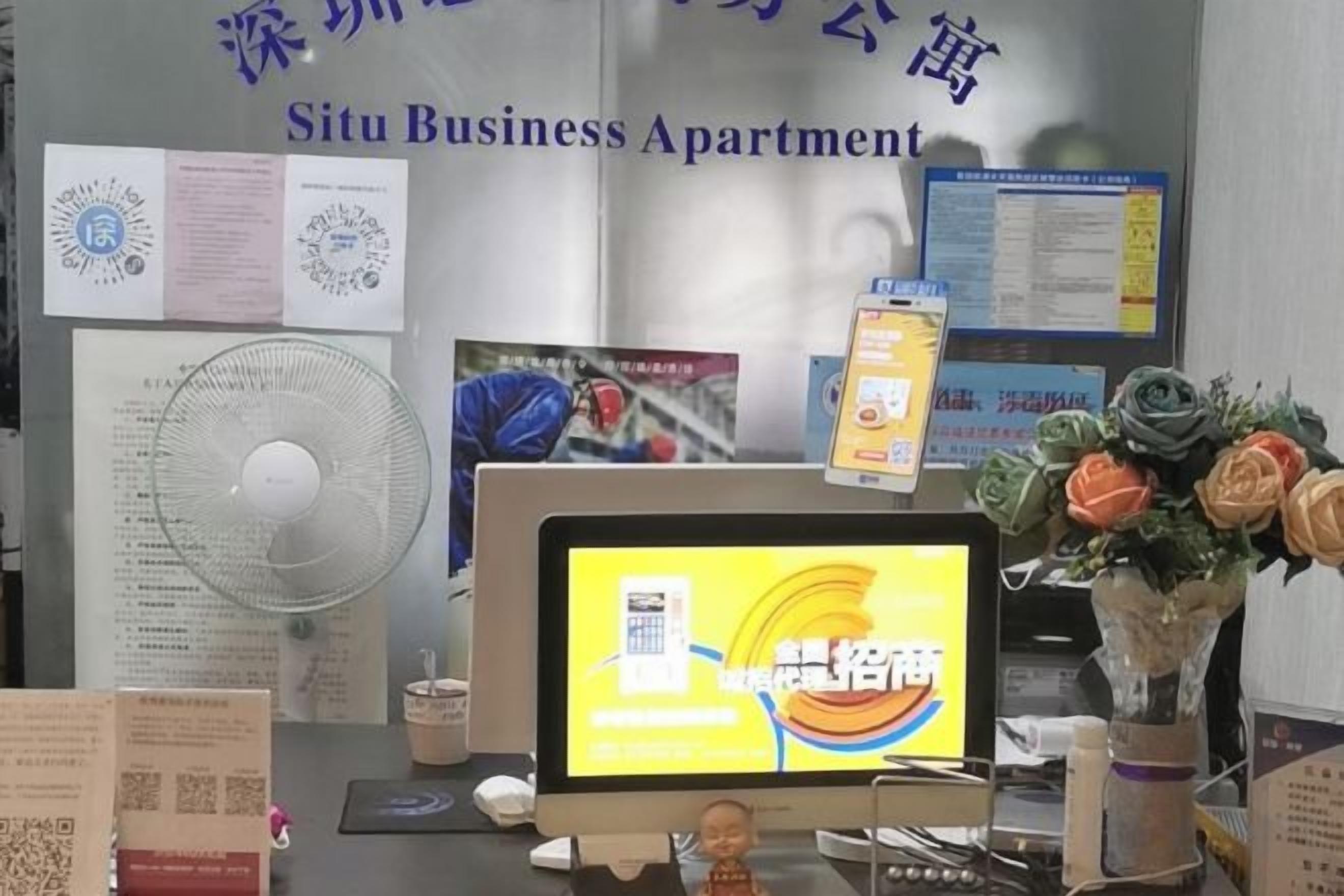 Apartamento para negócios com monitor de computador exibindo um mapa, um ventilador e diversos documentos na parede.