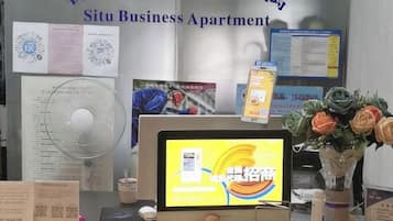 Apartamento para negócios com monitor de computador exibindo um mapa, um ventilador e diversos documentos na parede.