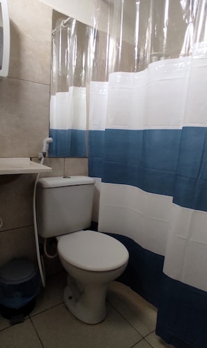 A small bathroom with a toilet, a sink, and a shower curtain. - Casa das Flores (Jijoca de Jericoacoara)