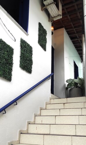 A staircase with beige steps leading to a landing, white walls, and green artificial foliage decorations. - Casa das Flores (Jijoca de Jericoacoara)