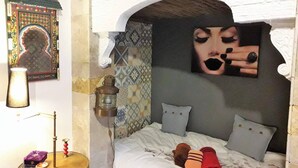 A cozy bedroom with a bed, pillows, a lamp, and a decorative wall piece.