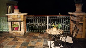 A patio with a tiled floor, a round table with chairs, and a decorative fence.