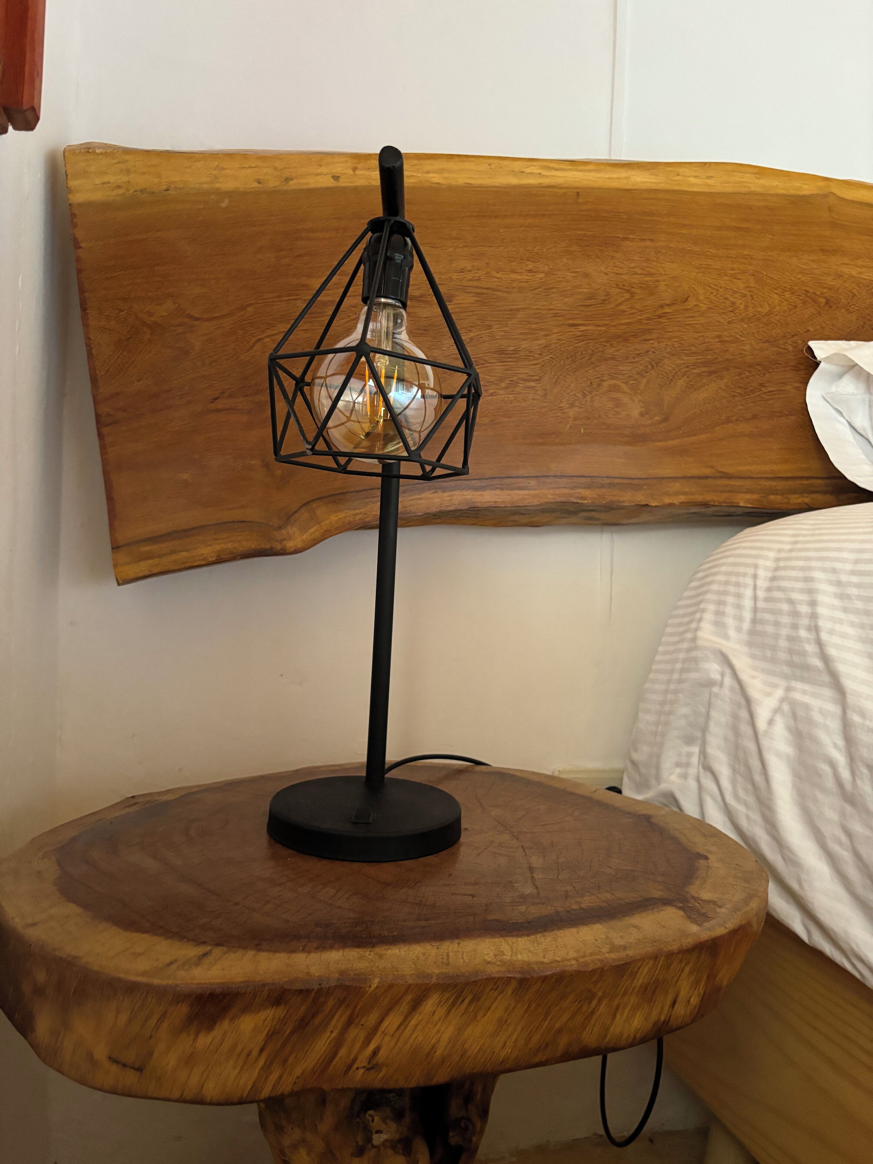 Een ronde houten tafel met een moderne lamp met een geometrisch glazen kap.