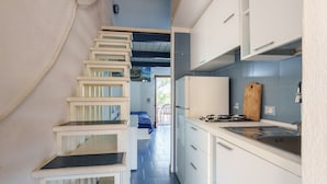 A narrow kitchen with white cabinets, a gas stove, and a blue tiled backsplash. - Casa Marebl in Palau (Palau)