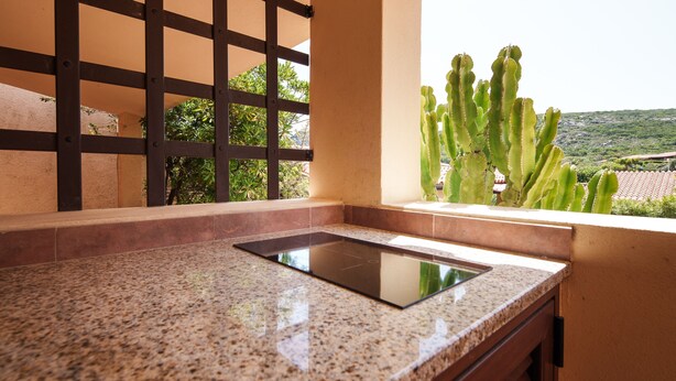 A kitchen with a granite countertop, a built-in stove, and a view of a cactus through a window. - Casa Marebl in Palau (Palau)