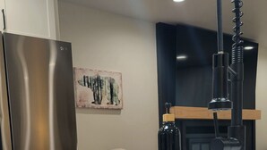 Una cucina moderna con un frigorifero in acciaio inossidabile, un rubinetto nero e una spugna blu sul piano di lavoro.